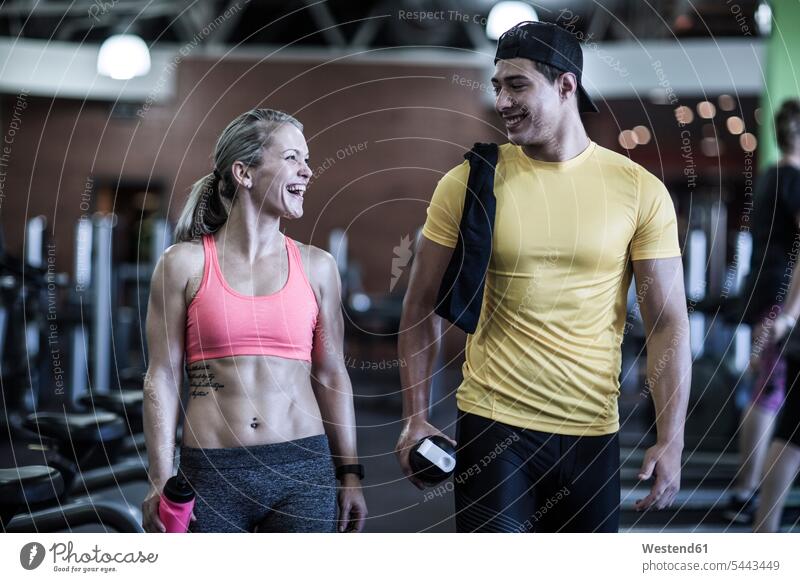 Happy young man and woman talking in gym laughing Laughter gyms Health Club exercising exercise training practising smiling smile positive Emotion Feeling