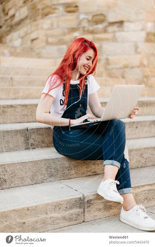 Redheaded woman sitting on stairs using laptop Laptop Computers laptops notebook females women music computer computers Adults grown-ups grownups adult people