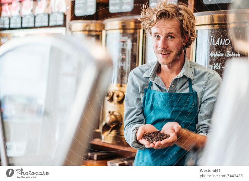 Portrait of coffee roaster in his shop holding coffee beans Coffee portrait portraits man men males smiling smile Drink beverages Drinks Beverage food and drink