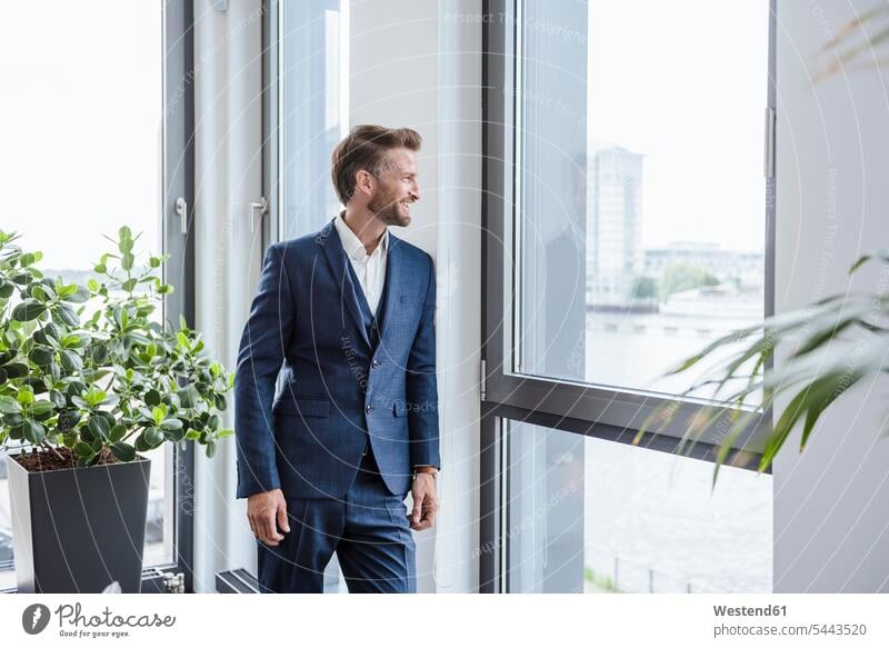 Relaxed businessman standing in his office looking out of the window Businessman Business man Businessmen Business men offices office room office rooms