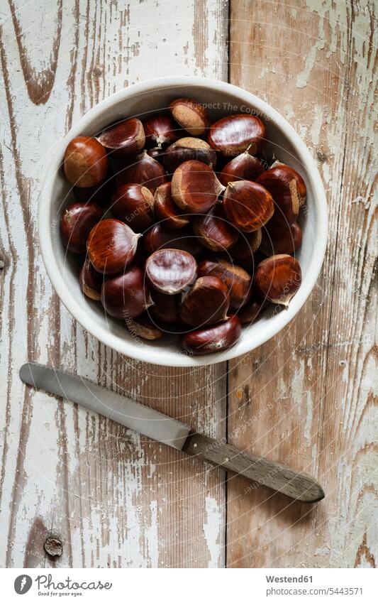Sweet chestnuts in a bowl and knife food and drink Nutrition Alimentation Food and Drinks large group of objects many objects wooden copy space Chestnut