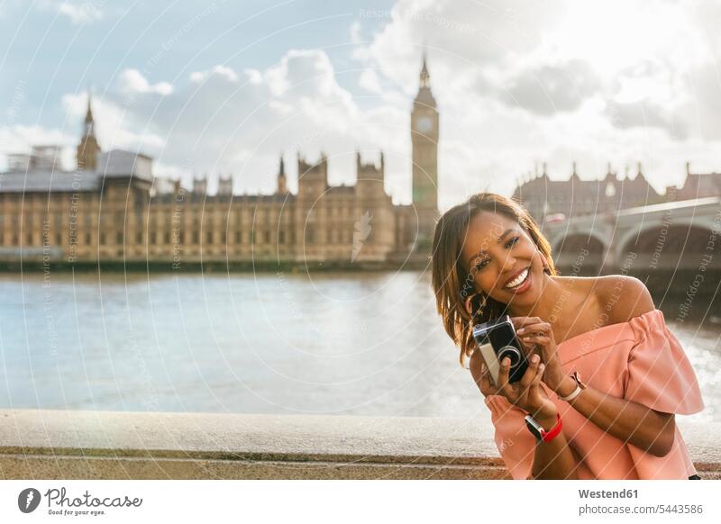 UK, London, happy woman holding a camera near Westminster Bridge cameras laughing Laughter females women positive Emotion Feeling Feelings Sentiments Emotions