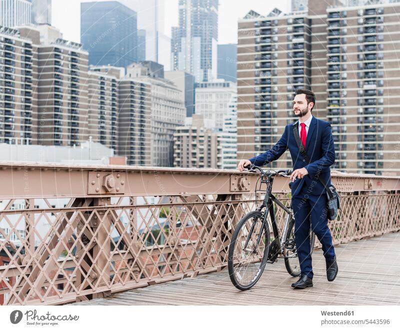 USA, New York City, businessman with bicycle on Brooklyn Bridge bikes bicycles New York State bridge bridges Businessman Business man Businessmen Business men