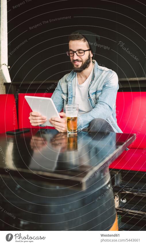 Smiling young man sitting in a pub using tablet digitizer Tablet Computer Tablet PC Tablet Computers iPad Digital Tablet digital tablets pubs tavern taverns men