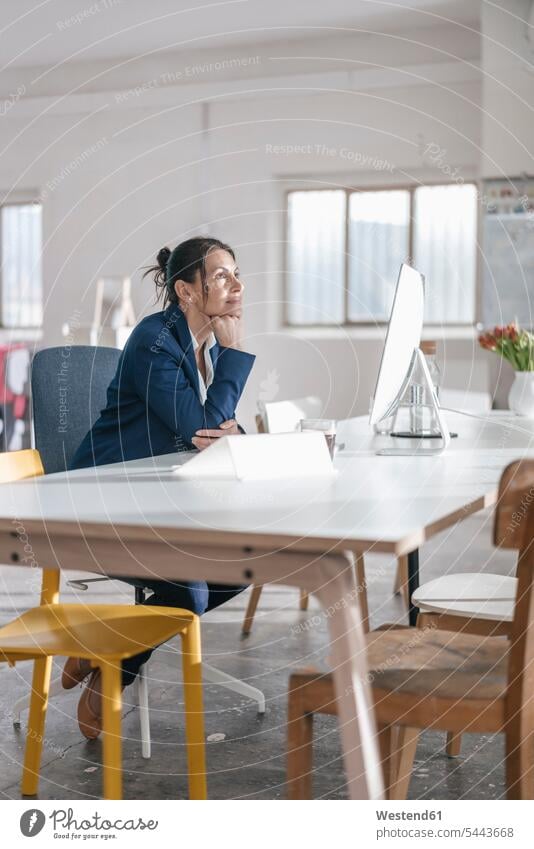 Pensive businesswoman sitting at desk in a loft desks businesswomen business woman business women females Table Tables business people businesspeople