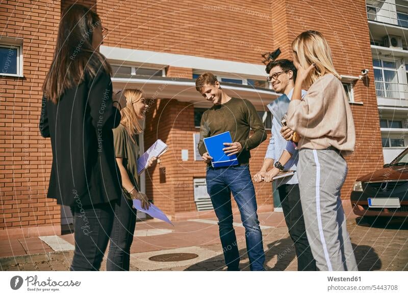 Group of happy students standing outdoors with documents group of people groups of people happiness studying persons human being humans human beings