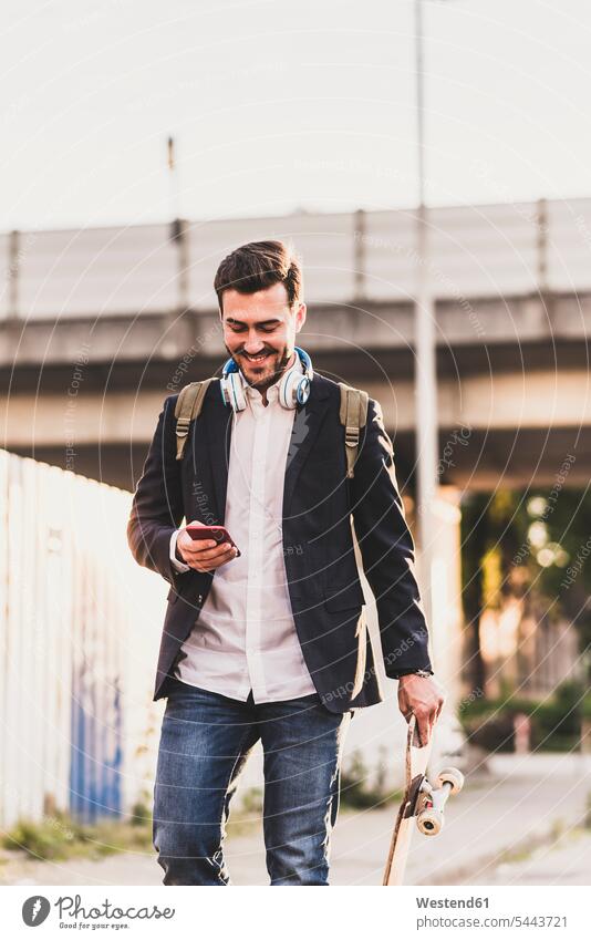 Smiling young man on the move checking cell phone smiling smile mobile phone mobiles mobile phones Cellphone cell phones men males telephones communication