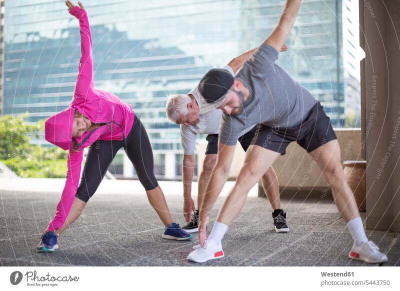Three athletes doing gymnastics in the city group groups Sportspeople Sportsman Sportsperson Sportsmen warming up warm up stretching exercising exercise