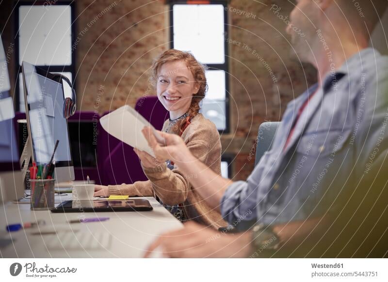 Young man helping colleague sitting at desk in office, smiling assistance assisting Help offices office room office rooms business people businesspeople