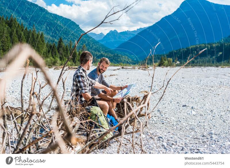 Germany, Bavaria, two hikers having a rest wanderers hiking sitting Seated river bed riverbed map maps Hiking Map Adventure adventurous Adventures