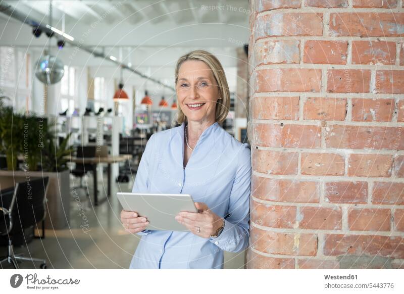 Mature businesswoman using digital tablet standing smiling smile consulting mature woman mature women businesswomen business woman business women digitizer