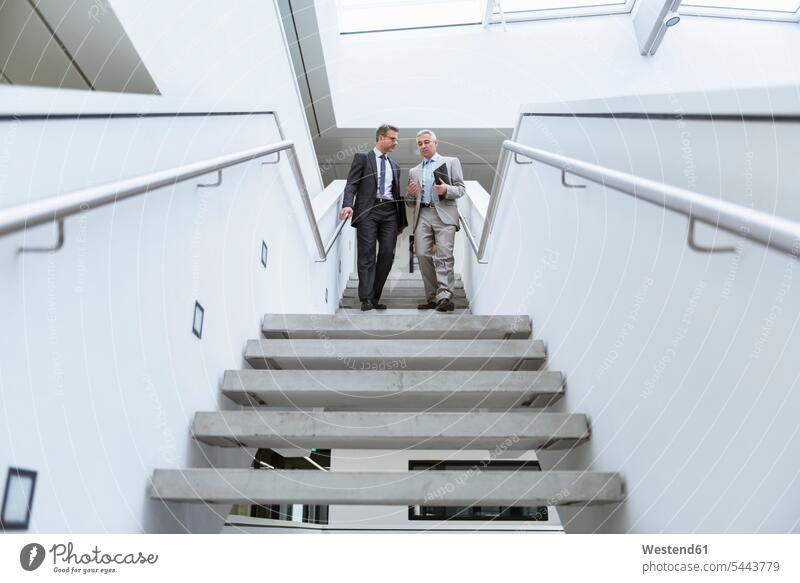 Two businessmen having an informal meeting Businessman Business man Businessmen Business men stairs stairway walking going together work meeting briefing