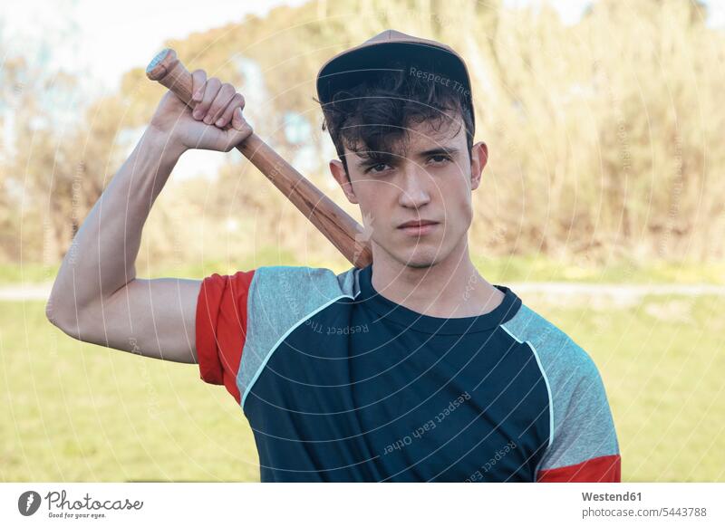 Portrait of young man with baseball bat in park men males Bat Sports Bat baseball player baseball players Adults grown-ups grownups adult people persons