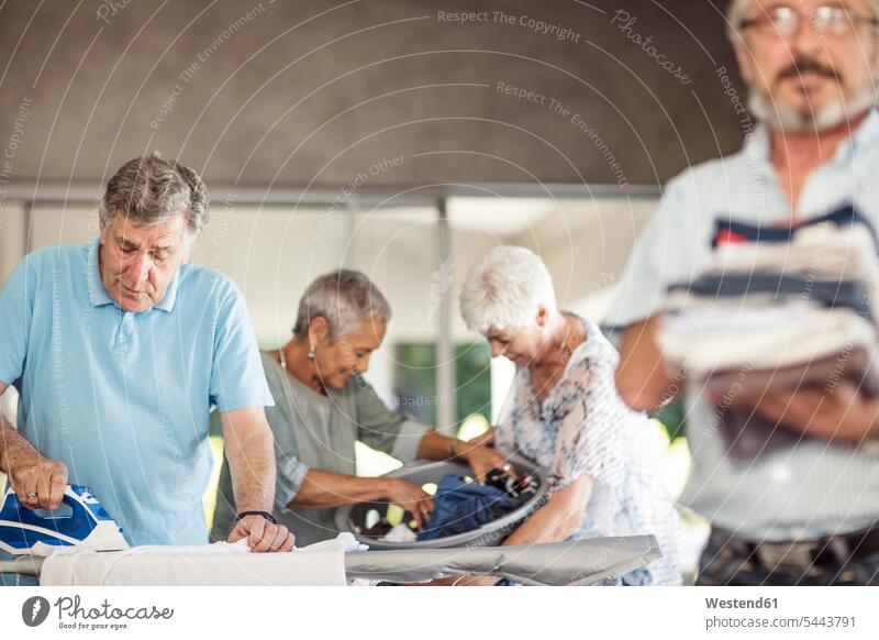 Seniors ironing clothes together friends friendship Household smiling smile senior men senior man elder man elder men senior citizen Laundry senior adults males