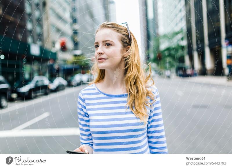 USA, New York, Manhattan, Young woman walking in the street, holding mobile phone females women blond blond hair blonde hair young Adults grown-ups grownups
