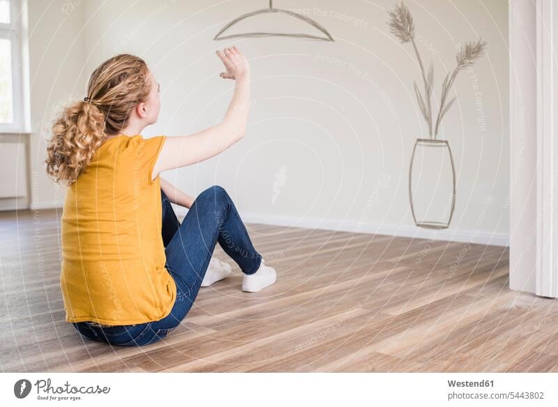 Young woman in new home sitting on floor thinking about interior design females women Seated flat flats apartment apartments Adults grown-ups grownups adult
