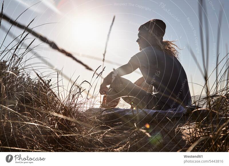 Portugal, Algarve, man sitting on the beach at sunset Seated beaches men males Adults grown-ups grownups adult people persons human being humans human beings
