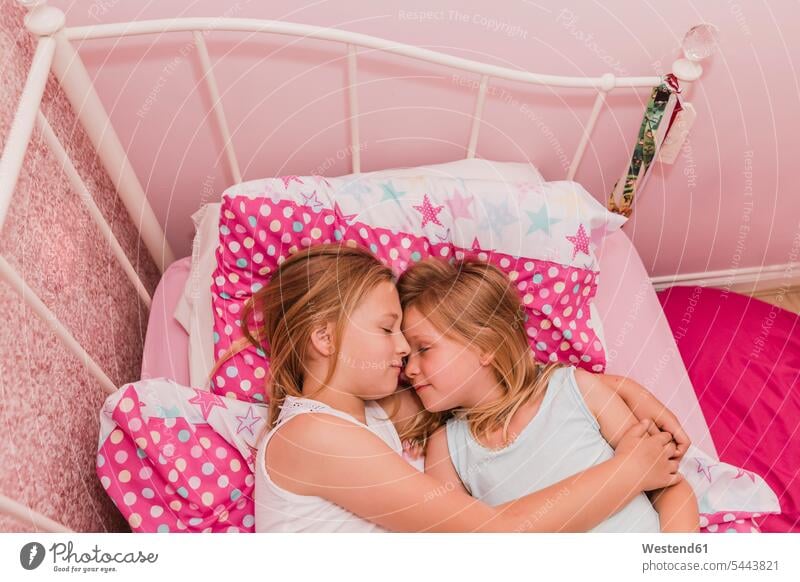 Two little sisters resting on bed beds girl females girls child children kid kids people persons human being humans human beings siblings brother and sister