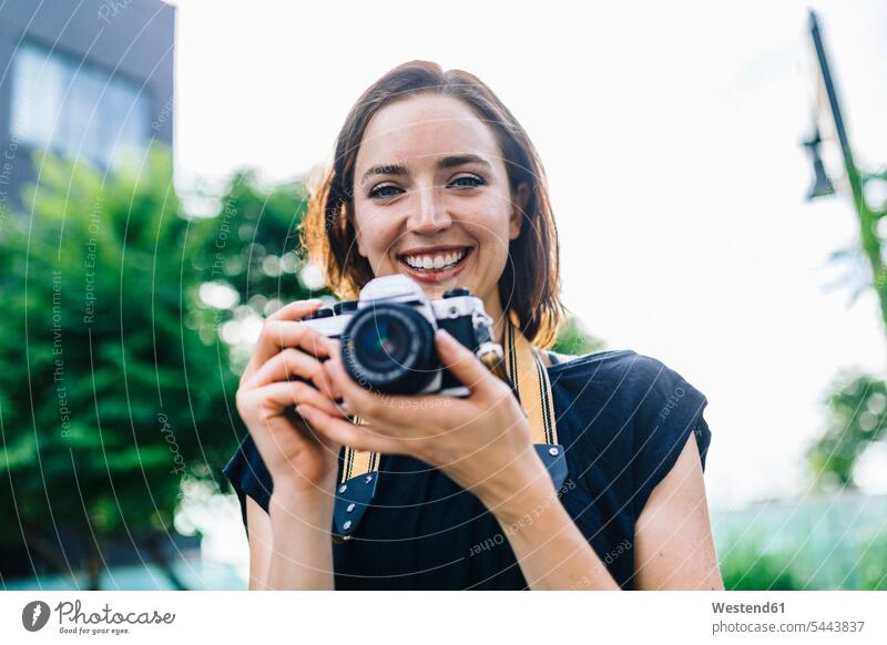 Portrait of smiling woman with camera cameras portrait portraits females women Adults grown-ups grownups adult people persons human being humans human beings