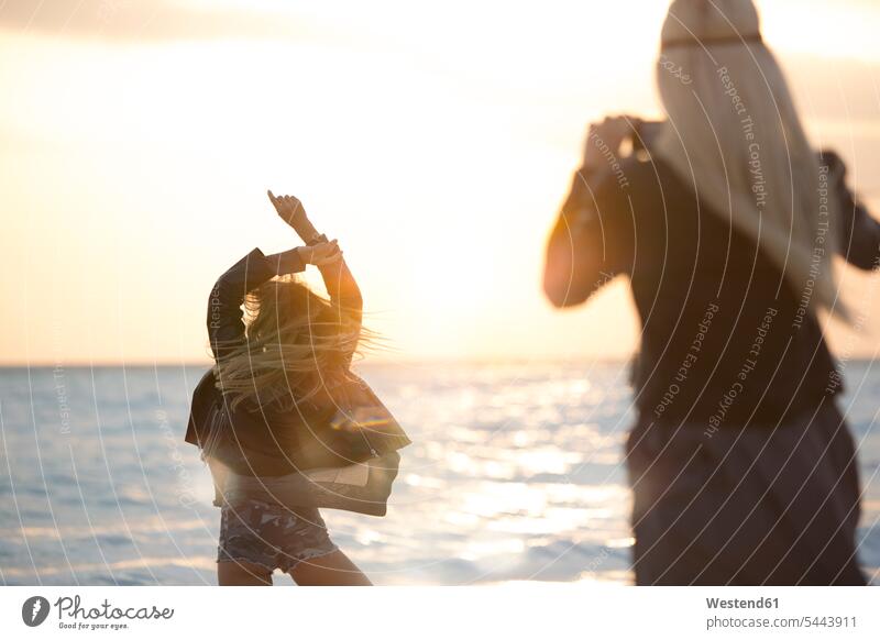Friends taking pictures on the beach at sunset happiness happy dancing dance romantic lyrical Romance Sea ocean beaches vacation Holidays water Travel sunshine