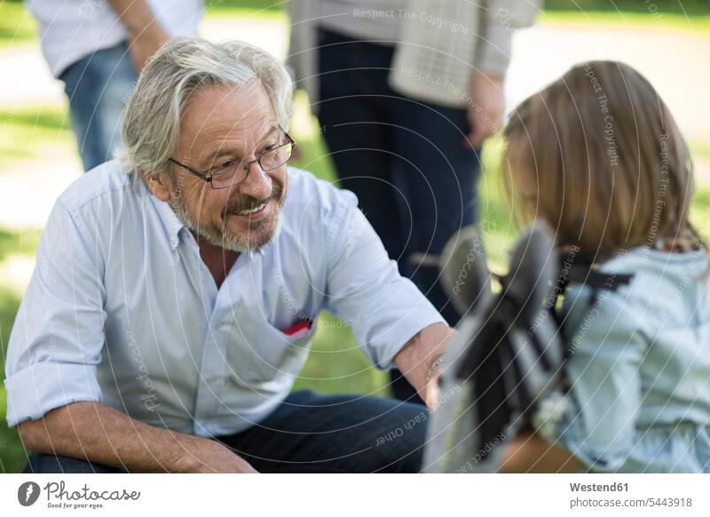 Smiling grandfather looking at granddaughter outdoors smiling smile family families grandpas granddads grandfathers granddaughters people persons human being