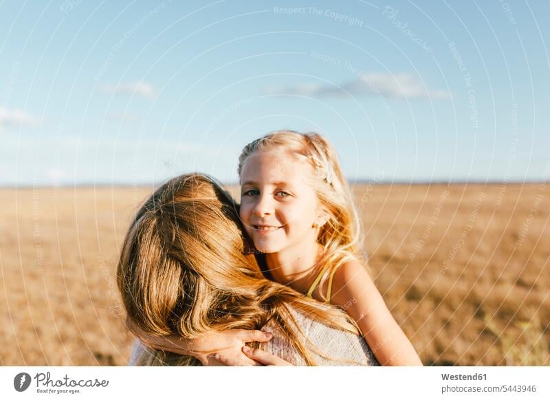 Portrait of smiling daughter hugging mother at a field embracing embrace Embracement mommy mothers ma mummy mama daughters Field Fields farmland smile parents