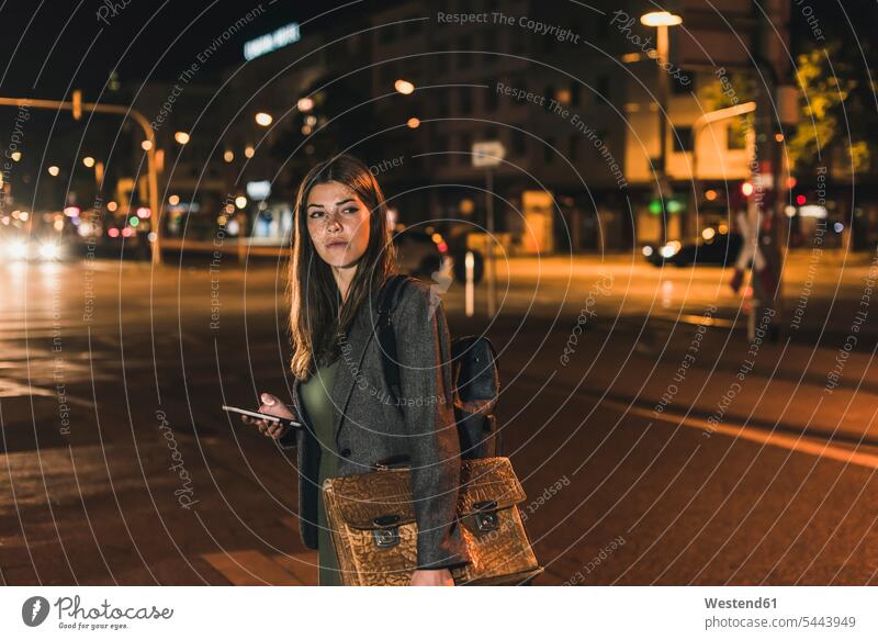 Portrait of young businesswoman with baggage and cell phone at night businesswomen business woman business women by night nite night photography business people