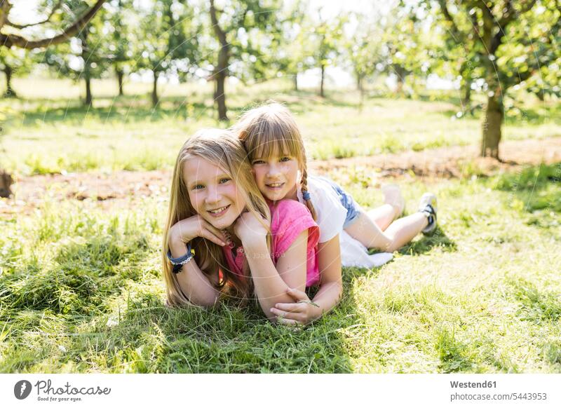 Two smiling sisters lying on meadow laying down lie lying down happiness happy meadows smile garden gardens domestic garden girl females girls siblings