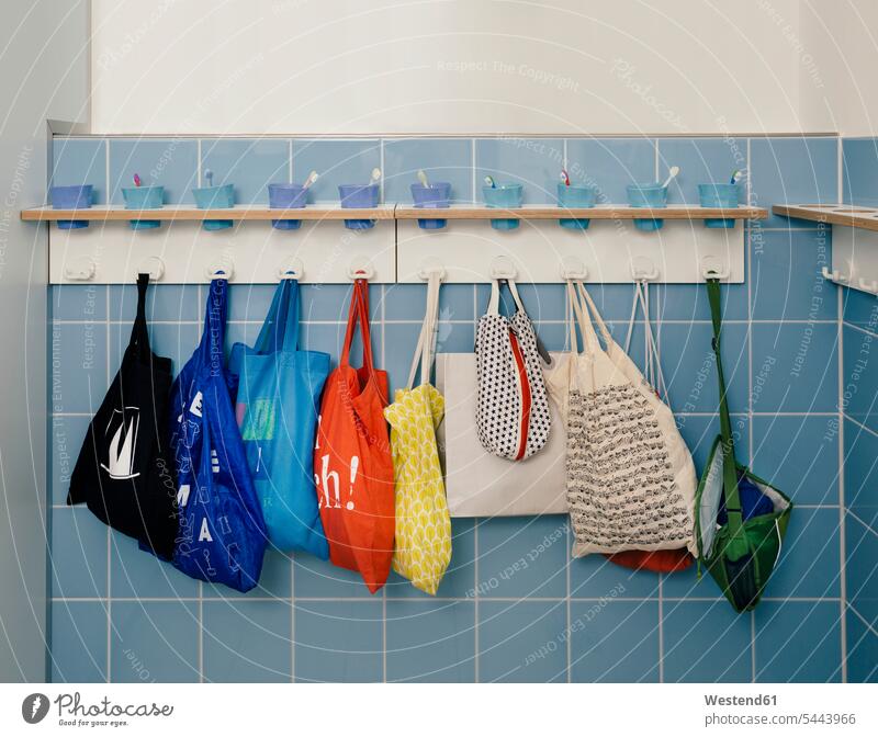 Line-up of of toothbrushes and bags on hooks in kindergarten in a row Rows toothbrush mug nursery school pedagogics Order Orderliness neat equipment Germany