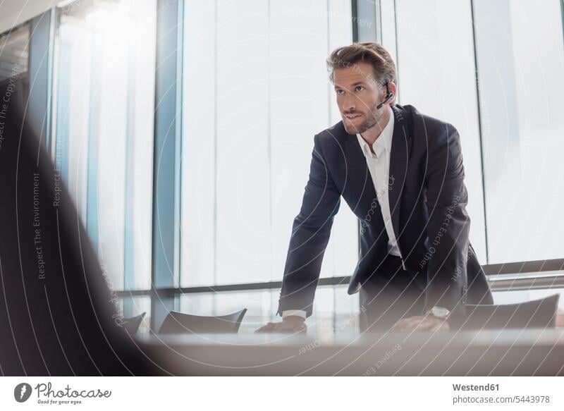 Portrait of businessman with bluetooth headset standing in conference room Businessman Business man Businessmen Business men portrait portraits on the phone
