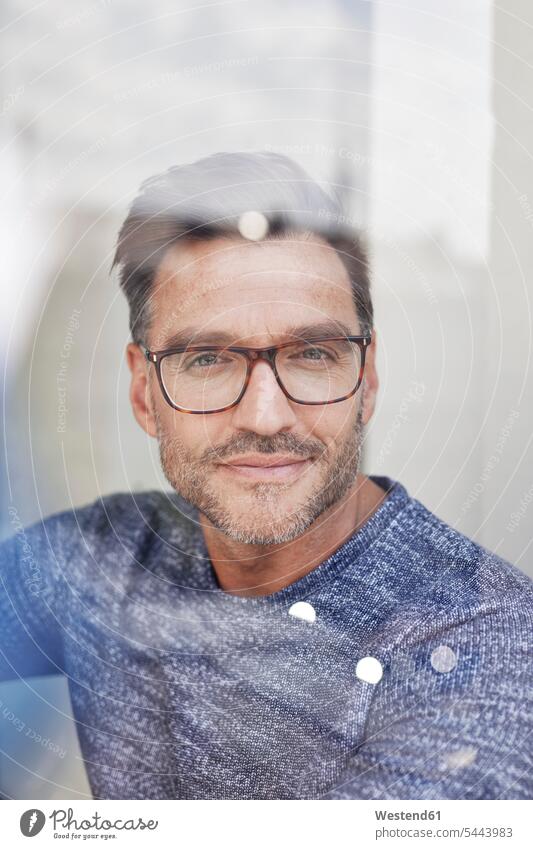 Portrait of smiling man behind glass pane wearing glasses smile portrait portraits men males glass panes smart specs Eye Glasses spectacles Eyeglasses Adults