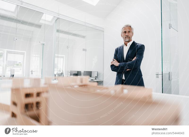 Mature businessman with architectural model in office offices office room office rooms architects models Businessman Business man Businessmen Business men