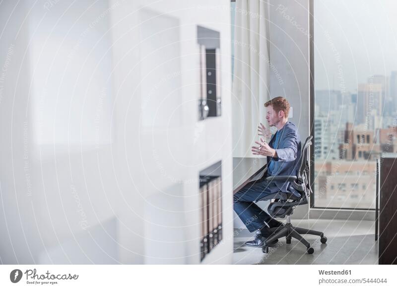Man sitting at desk in city office Seated Businessman Business man Businessmen Business men offices office room office rooms business people businesspeople