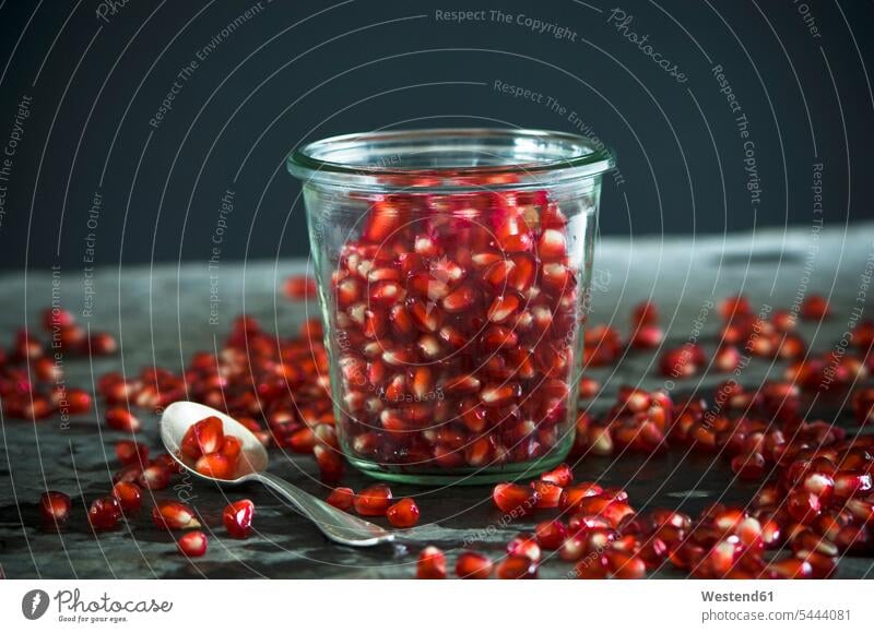 Glass of pomegranate seeds and tea spoon scattered nobody copy space schist slates still life still-lifes still lifes healthy eating nutrition Glasses close-up
