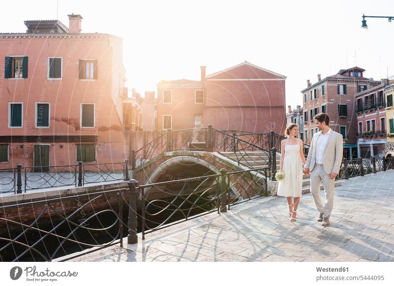 Italy, Venice, bridal couple walking hand in hand at sunrise bridal couples married couple married couples marriage people persons human being humans