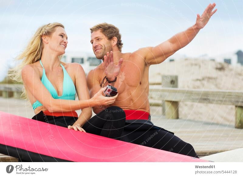 Happy couple with surfboard talking on the beach twosomes partnership couples beaches surfboards people persons human being humans human beings surfing