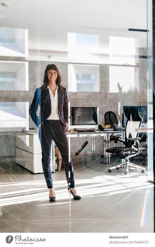Successful businesswoman standing in office with hands in pockets expertise competence competent Office Offices happiness happy businesswomen business woman