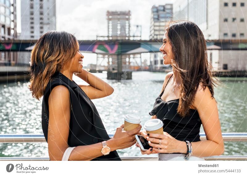 Two women having a coffee break on a bridge in the city Coffee smiling smile woman females Female Colleague Drink beverages Drinks Beverage food and drink