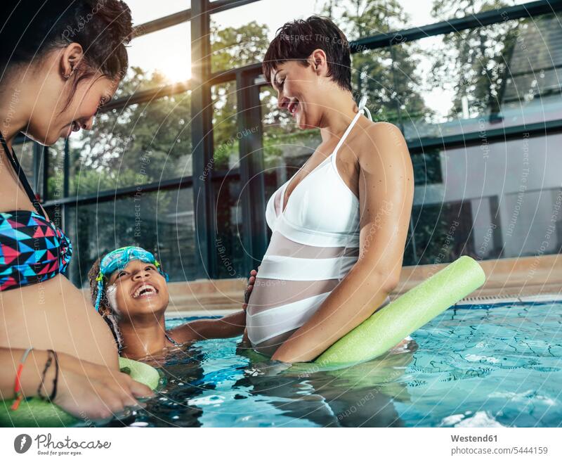 Two pregnant women with daughter doing water gymnastics in indoor swimming pool indoor swimming pools swimming bath Pregnant Woman woman females aqua aerobics