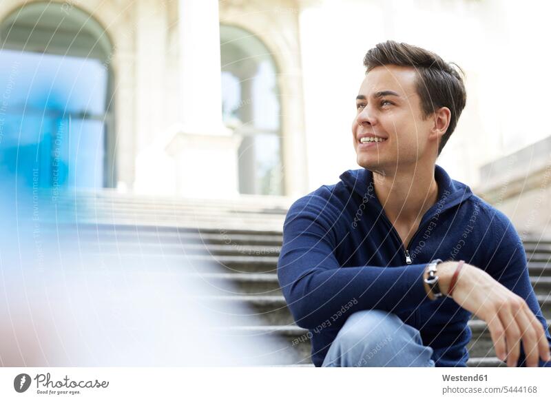 Portrait of laughing young man sitting on stairs men males Adults grown-ups grownups adult people persons human being humans human beings stairway Seated steps