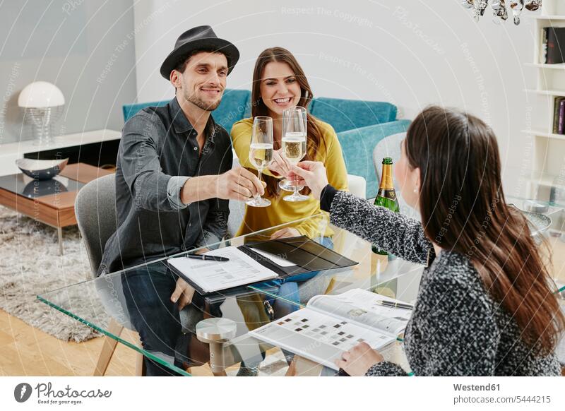 Couple celebrating sales contract in furniture store Furniture Furnitures toasting clinking cheers couple twosomes partnership couples shopping celebrate