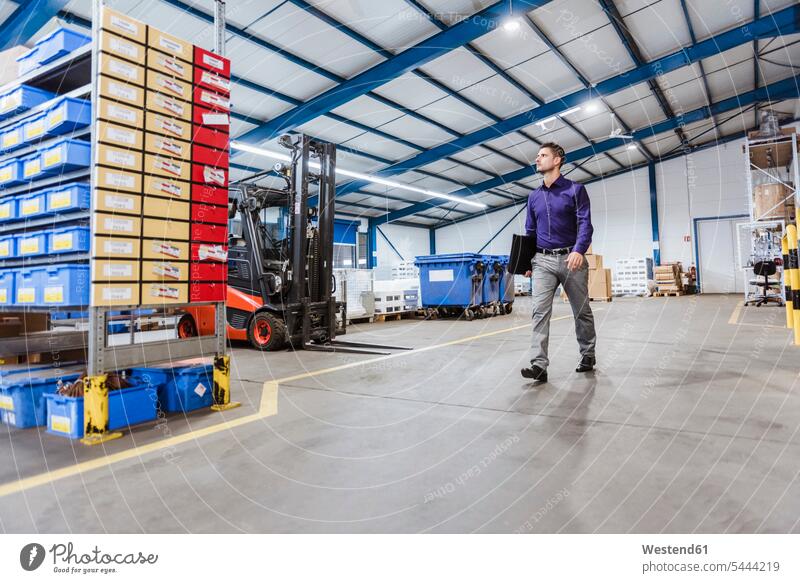 Businessman walking through shop floor, holding files working At Work production hall factory Business man Businessmen Business men industry industrial