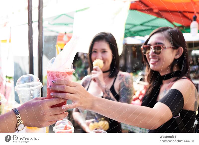 Woman buying a smoothie from a street vendor in Thailand smiling smile woman females women Smoothies Street Trader Street Traders street vendors Adults