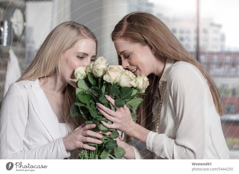 Two young women smelling roses at home female friends smiling smile Bunch of Flowers Bouquet Flower Bouquet Bouquet of Flowers Flower Bouquets