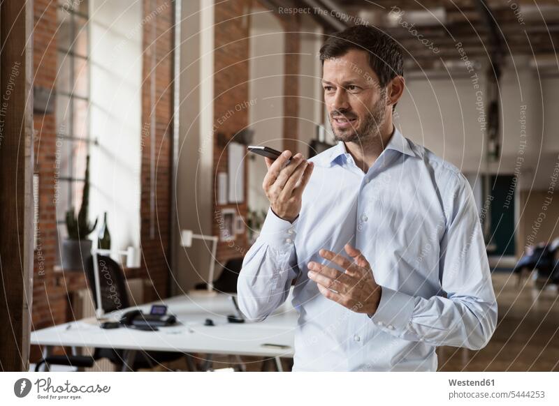 Businessman using cell phone in office mobile phone mobiles mobile phones Cellphone cell phones Business man Businessmen Business men offices office room
