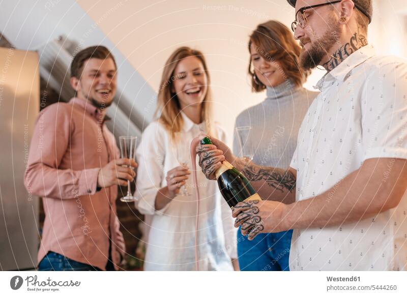 Man opening Champagne bottle while his friends watching man men males Adults grown-ups grownups adult people persons human being humans human beings