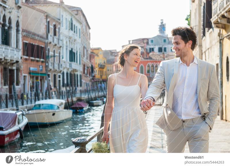 Italy, Venice, happy bridal couple walking hand in hand at morning twilight bridal couples married couple married couples marriage people persons human being