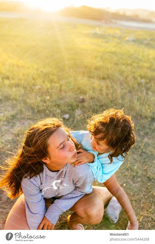 Girl and little sister playing together at sunset sisters girl females girls siblings brother and sister brothers and sisters family families people persons