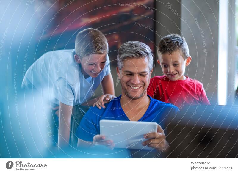 Children looking with their father on digital tablet family families pa fathers daddy dads papa smiling smile son sons manchild manchildren digitizer
