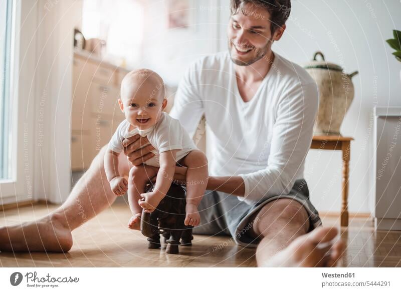 Happy father with baby girl playing at home infants nurselings babies pa fathers daddy dads papa smiling smile people persons human being humans human beings